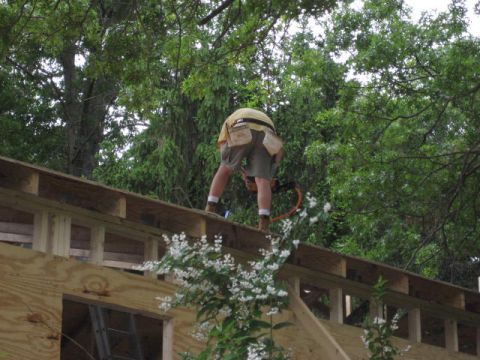 1996 Ford Bronco - A worker is on the roof of a partially built structure, surrounded by lush green trees.
