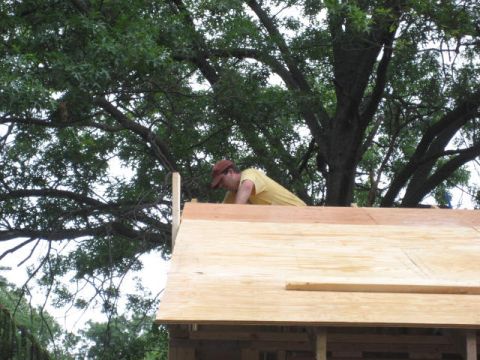 1996 Ford Bronco - A person works on framing a new wooden structure under a large tree.