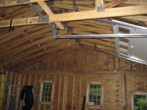 1996 Ford Bronco - Interior view of a garage showing exposed wooden beams, unfinished walls, windows, and a partially raised garage door.