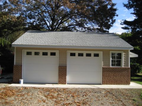 1996 Ford Bronco - A two-car garage with a gray shingled roof and tan siding is shown under a blue sky.
