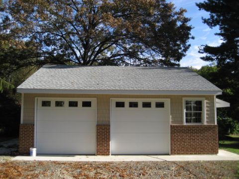 1996 Ford Bronco - A detached two-car garage features white overhead doors and a brick foundation, set against a backdrop of trees.