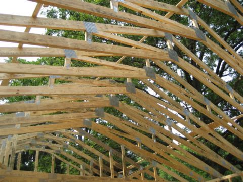 1996 Ford Bronco - Construction of a wooden roof structure with visible trusses and metal bracing against a backdrop of trees.