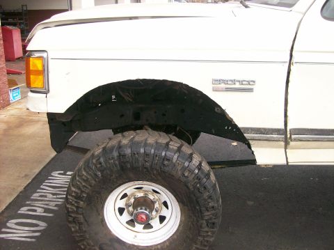 1989 Ford Bronco - A white Ford Bronco is shown from the front quarter, highlighting its large tire and fender area.