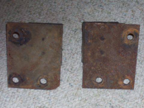 1979 Ford Pickup - Two rusty metal mounting brackets sit on a carpeted surface.