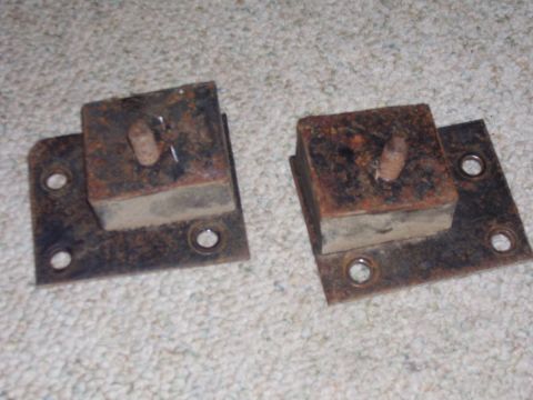1979 Ford Pickup - Two old, rusted mounting brackets with rubber dampeners are shown on a carpeted surface.