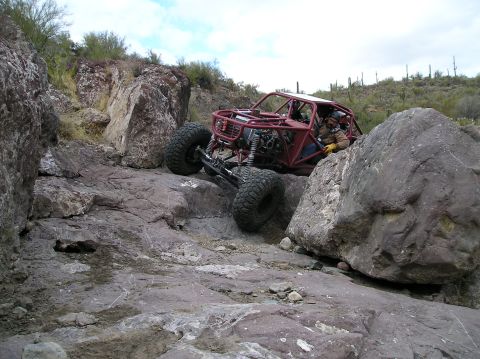 1986 Toyota Hilux - This custom-built off-road vehicle is designed for extreme terrain, tackling boulders in a desert landscape.