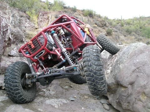 1986 Toyota Hilux - Custom off-road buggy tackles a challenging rock climb in a desert environment.