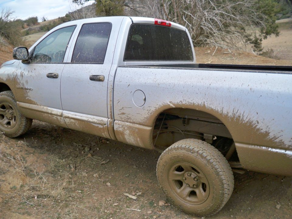 Silver pickup truck covered in mud, seen from the side