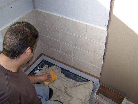 1991 Ford Bronco - A person is shown tiling a shower stall, with beige tiles on the wall.