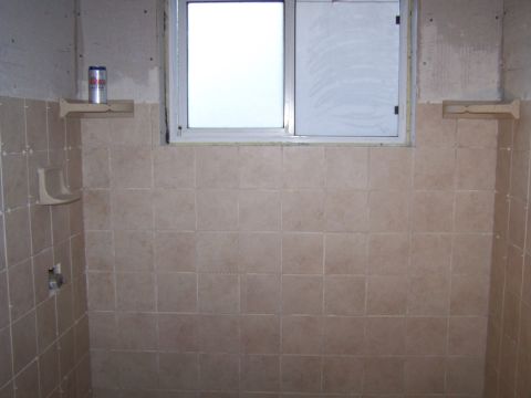 1991 Ford Bronco - A partially tiled shower stall with a window and a beer can on a shelf shows ongoing renovation work.