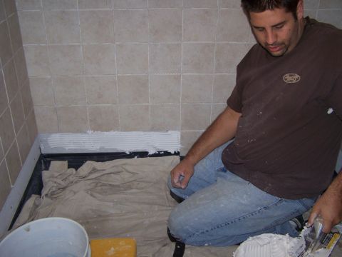 1991 Ford Bronco - Bathroom tiling in progress with a worker applying mortar to the wall.