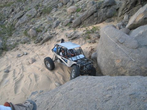 1992 Toyota Tacoma - A custom-built off-road buggy navigates a challenging desert terrain with steep inclines and large boulders.