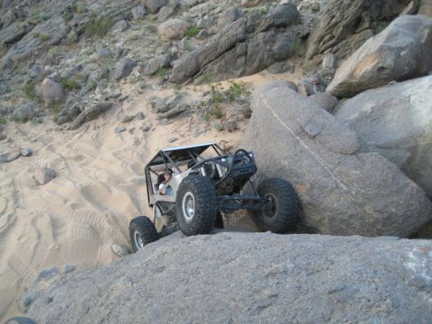 1992 Toyota Tacoma - Custom off-road buggy climbing over large rocks on a sandy hill.