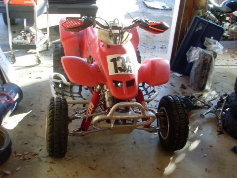 1987 Honda 250 R - Front view of a red ATV parked indoors with various items in the background.