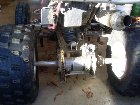 1987 Honda 250 R - Close-up view of the rear axle and chain drive assembly on an all-terrain vehicle.