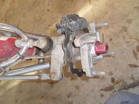 1987 Honda 250 R - Close-up of an ATV's front wheel hub assembly, showing the brake caliper and suspension linkages.