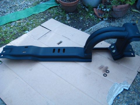 1989 Ford Bronco - A black metal component with curved tubes is shown laid out on cardboard.