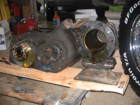 1978 Ford Bronco - A transfer case is shown resting on wooden blocks in a garage setting.