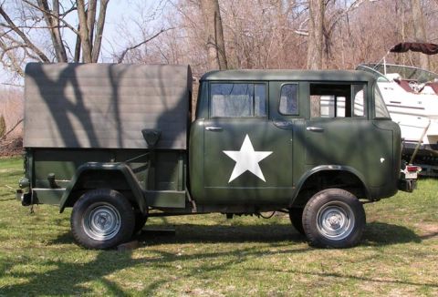 1991 Ford Bronco - A vintage military truck with a canvas cover is parked on a grassy area next to a boat.