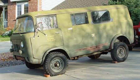 1991 Ford Bronco - Small olive-drab cab-over military-style Jeep FC panel van sitting on a driveway with wheels chocked, shown from the driver's front three-q…