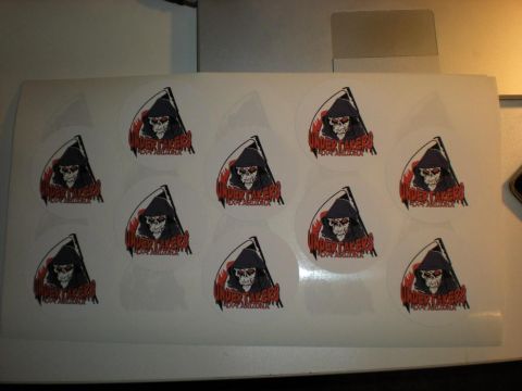 Suzuki Samurai - A sheet of round die-cut club decals lying on a desk, each printed with a hooded grim reaper holding a scythe over the red text "UNDERTAKER…