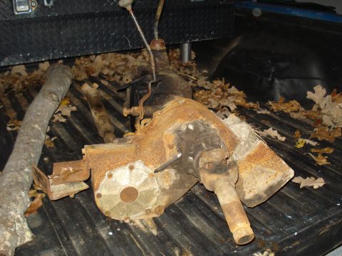 1991 Ford Bronco - A heavily rusted transfer case sits in the bed of a pickup truck amongst fallen leaves.