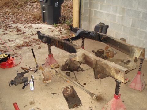 1991 Ford Bronco - Disassembled vehicle frame and axles are staged for repair or restoration.