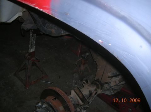 1985 Ford Bronco - The rear axle and suspension components are visible, supported by jack stands, beneath a vehicle's fender.