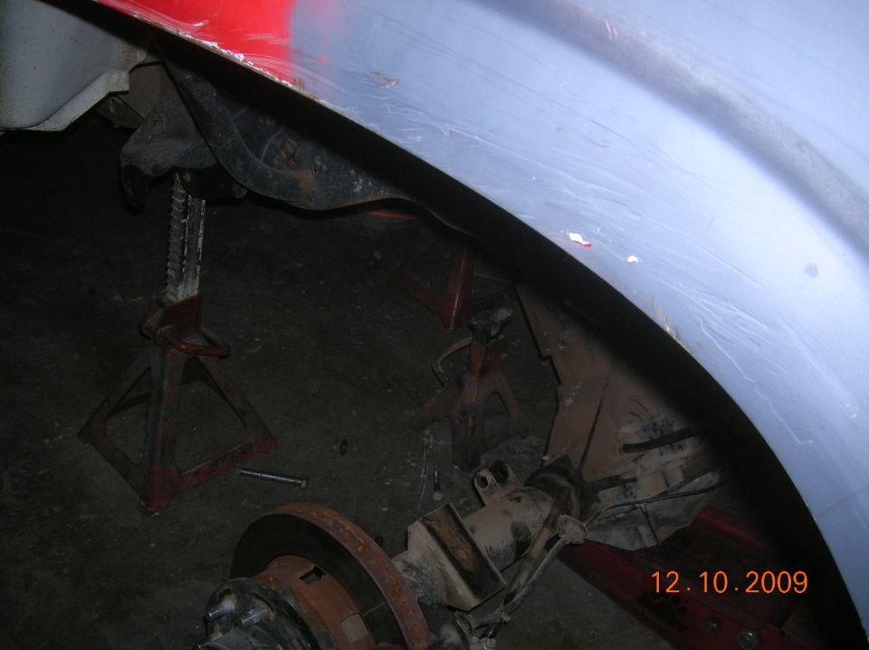Rear axle and suspension on jack stands, under a vehicle's fender