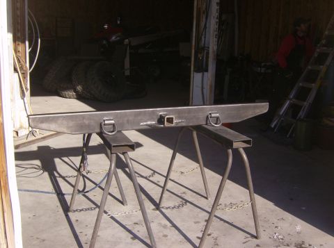 1989 Ford Bronco - A custom metal bumper assembly is displayed on sawhorses, ready for installation.