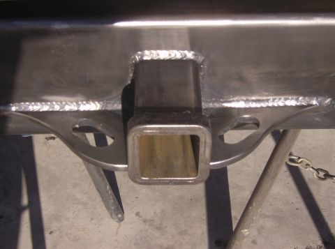 1989 Ford Bronco - Close-up of a trailer hitch receiver, showing the welded construction and a metal chain attached.