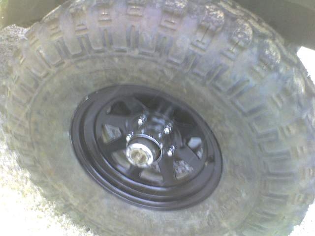 Close-up of a large, knobby off-road tire on a black wheel