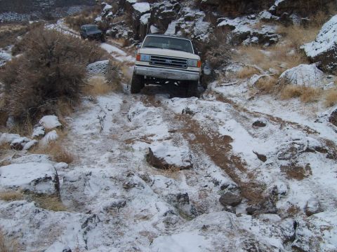 1989 Ford Bronco - Ford Bronco navigates a challenging snowy terrain, with another vehicle in the background.