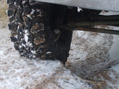 1989 Ford Bronco - Close-up view of a vehicle's tire and suspension system in a snowy environment.