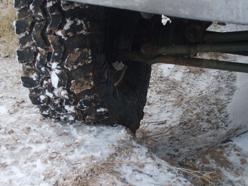 Tire with snow and mud, showing suspension linkage and frame