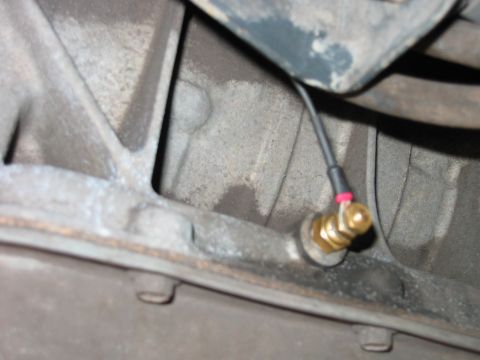 1992 Ford Bronco - A sensor with a wire is attached to the underside of a vehicle's transmission.