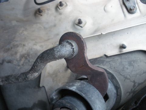 1990 Ford Bronco - Steering column linkage with visible rust and a black rubber bushing.