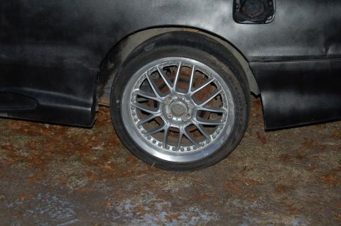 1997 Mazda MX-6 - A close-up shot focuses on the rear wheel and black fender of a car, with the fuel door visible.