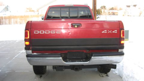 1997 Dodge 2500 - The rear of a red Dodge pickup truck is shown with a chrome bumper and a 4x4 decal on the tailgate.