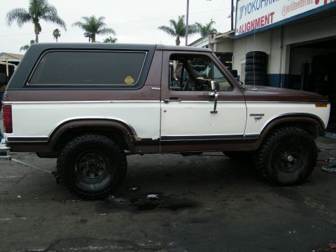 1982 Ford Bronco - This two-tone Ford Bronco, likely from the early 1980s, is seen from the side in front of a Yokohama tire shop.