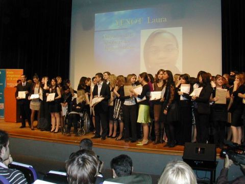 1991 Ford Crown Victoria - Students receive awards on stage during a graduation ceremony, with a projector screen displaying names and images.