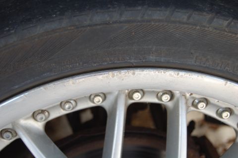 1997 Mazda MX-6 - Close-up view of a car wheel and tire, showing lug nuts and sidewall markings.