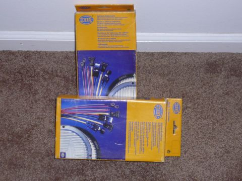 1988 Ford Bronco - HELLA wiring harness boxes are displayed on a carpeted surface, showing product details and branding.