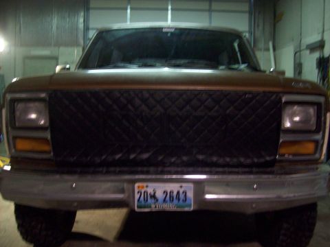 1985 Ford Bronco - This 1985 Ford Bronco is seen from the front, a quilted black grille cover and a Wyoming license plate.