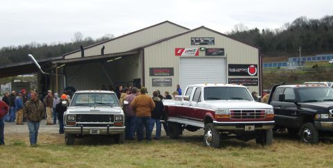 2007 Ford Mustang - Several pickup trucks are parked outside a building with a crowd of people.