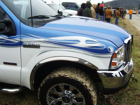 2007 Ford Mustang - A white and blue Ford F-250 truck with custom flame graphics is parked at an outdoor event.