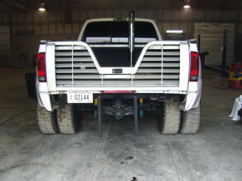 2007 Ford Mustang - This dually pickup truck features a custom bed with horizontal slats and a prominent exhaust pipe, seen from the rear.