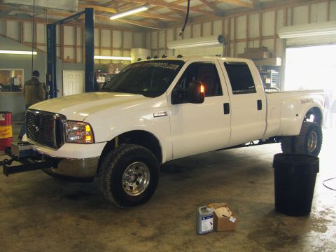 2007 Ford Mustang - A white Ford F-350 Super Duty pickup truck is parked inside a garage with a vehicle lift.