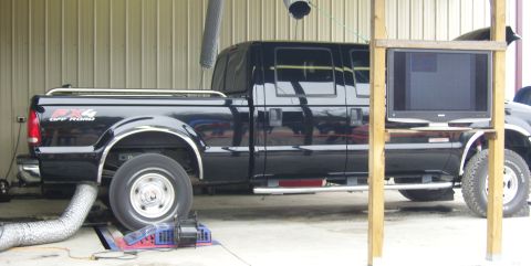 2007 Ford Mustang - A black crew cab pickup truck is positioned on a dynamometer for testing inside a garage.