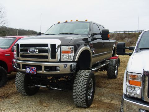 2007 Ford Mustang - A lifted Ford truck with a Confederate flag license plate is parked next to another vehicle.